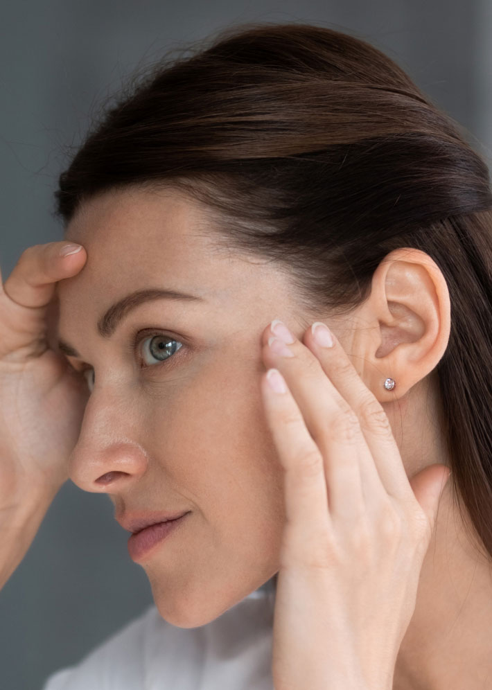 woman inspecting facial skin